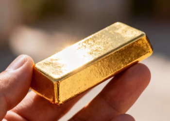 Main d'or tenant une barre d'or brillante.