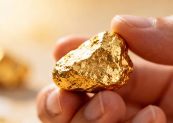 Main d'une personne tenant une pépite d'or brillante.