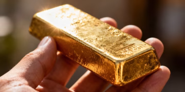 一位網紅的手拿著一根閃亮的金條。