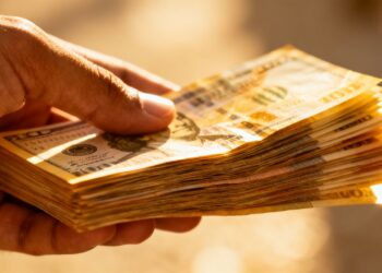 Main d'une personne tenant de l'argent liquide.