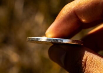 Main d'une personne tenant une pièce d'argent.
