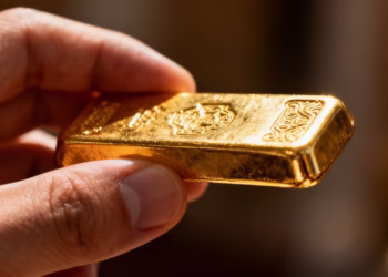 Main d'une personne tenant une barre d'or