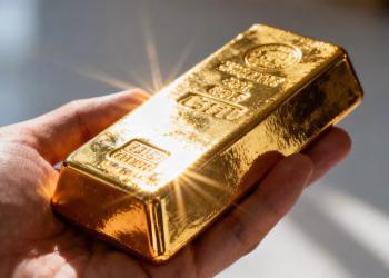 Main d'une personne tenant une barre d'or brillante.