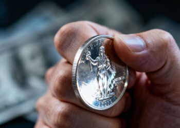 Main d'une personne tenant une pièce d'argent.