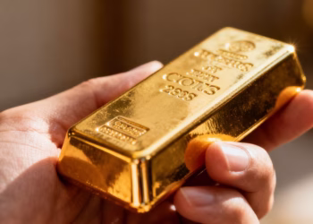 Une main tenant une barre d'or brillante.