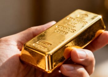 Une main tenant une barre d'or brillante.