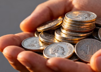 A person's hand holding silver coins.