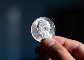 A person's hand holding a silver coin.