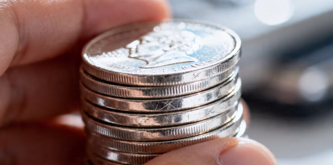 Main d'une personne tenant une pile de pièces d'argent.