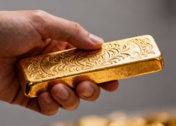 Main d'une personne tenant une barre d'or brillante.