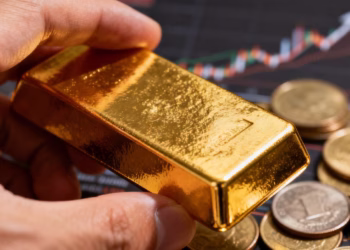 Main d'or tenant une barre d'or avec des pièces floues.