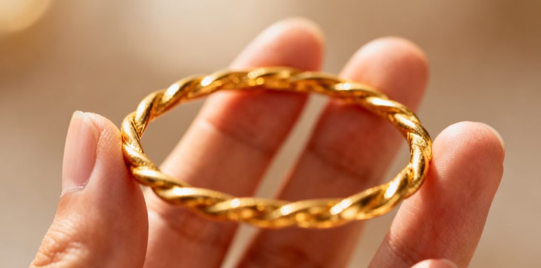 يد شخص تمسك بسوار ذهبي.
