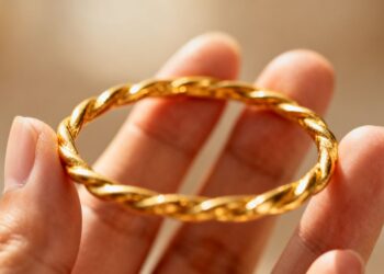 يد شخص تمسك بسوار ذهبي.