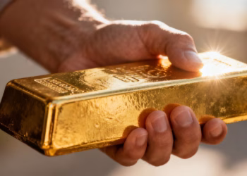 Main d'or tenant une barre d'or brillante.