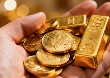 Main d'expert tenant des lingots et pièces d'or.