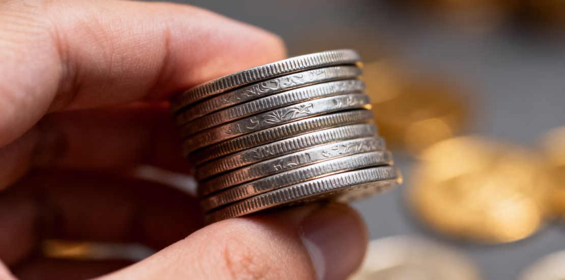 Main d'une personne tenant des pièces d'argent.