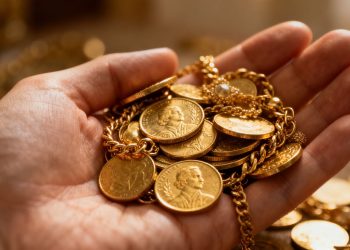 Main d'or tenant des pièces et des bijoux en or