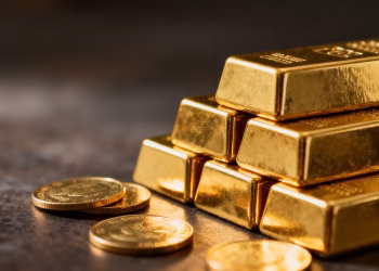 Lingots et pièces d'or brillants sur fond sombre.