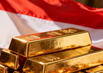 Lingots d'or devant un drapeau indonésien en lumière vive.