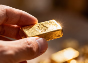 Main d'or tenant une barre d'or brillante