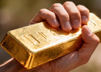 Une main tenant une barre d'or brillante.