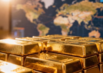 Lingots d'or brillants sur fond flou de carte du monde.