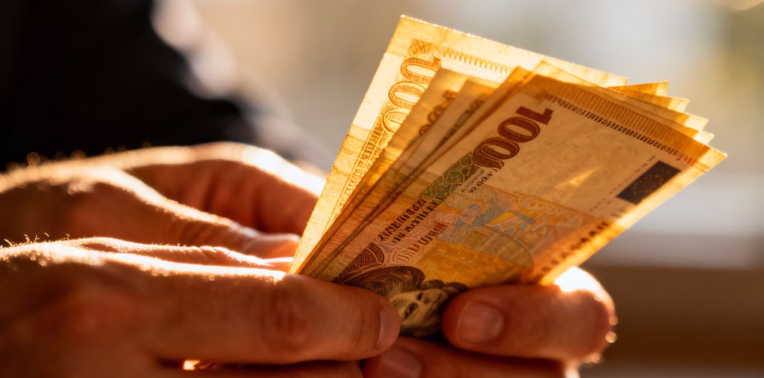 Mains tenant une liasse de billets de banque à domicile.