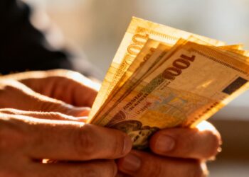 Mains tenant une liasse de billets de banque à domicile.