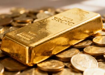 Lingots d'or et pièces d'or brillants sous la lumière.