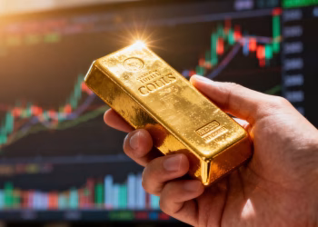 Main d'or tenant une barre d'or brillante.