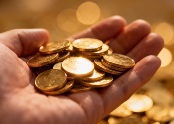 Main d'or tenant des pièces d'or brillantes