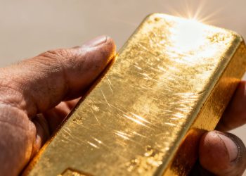 Main d'une personne tenant une barre d'or brillante.