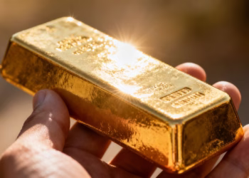 Main d'or tenant une barre d'or brillante.