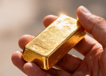 Main d'or tenant une barre d'or brillante.