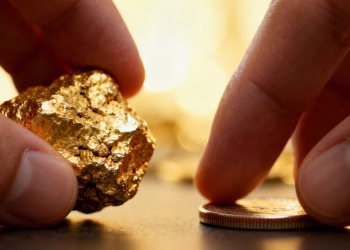 Main d'or tenant une pépite d'or et une pièce.