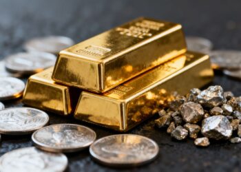 Lingots d'or et pièces d'argent sur fond sombre.