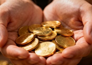 Mains tenant des pièces d'or brillantes, gros plan.