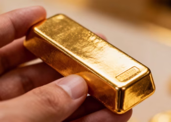 Main d'une personne tenant une barre d'or brillante.