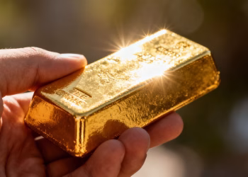 Main d'une personne tenant une barre d'or brillante.