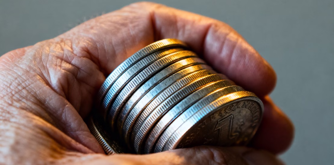 Main d'une personne tenant des pièces d'argent pour la transmission de patrimoine.