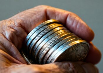 Main d'une personne tenant des pièces d'argent pour la transmission de patrimoine.