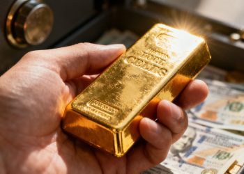 Main d'une personne tenant une barre d'or brillante.