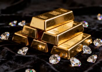 Lingots d'or et diamants brillants sur fond sombre.