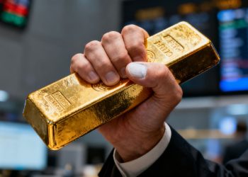 Mains serrant une barre d'or, stress au trading.