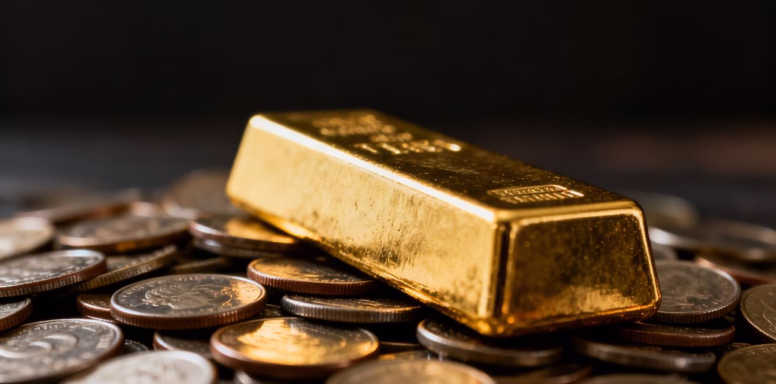 Barre d'or sur des pièces de monnaie éparpillées.
