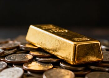 Barre d'or sur des pièces de monnaie éparpillées.