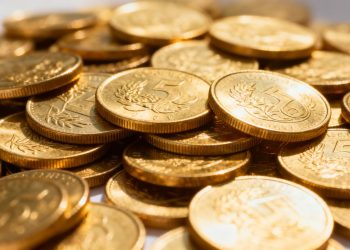 Moedas de ouro brilhantes empilhadas, em close-up.