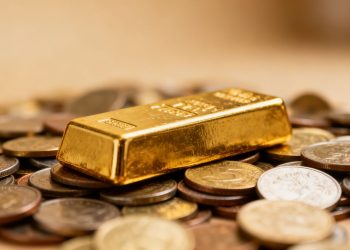 Barre d'or sur des pièces, symbole de richesse et de crise économique.