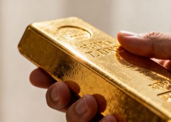 Main d'or tenant une barre d'or brillante.