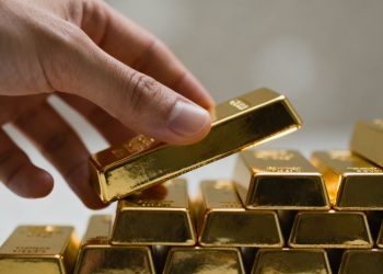 Main d'or plaçant une barre d'or sur une pile.